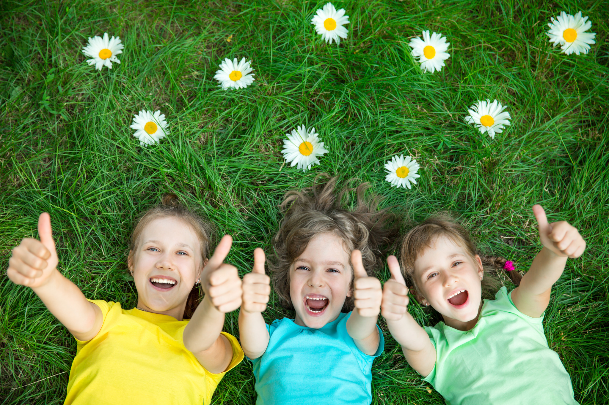 3 lachende Kinder im Gras mit